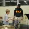 Brother Jenkins being taught to play snare drum by a student